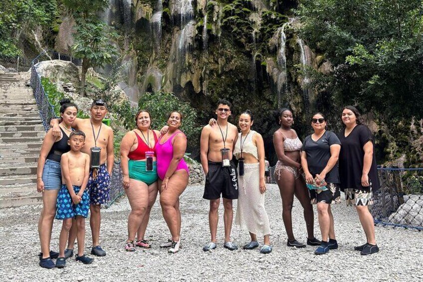 A group of people standing on a rocky path with a waterfall in the background. 2