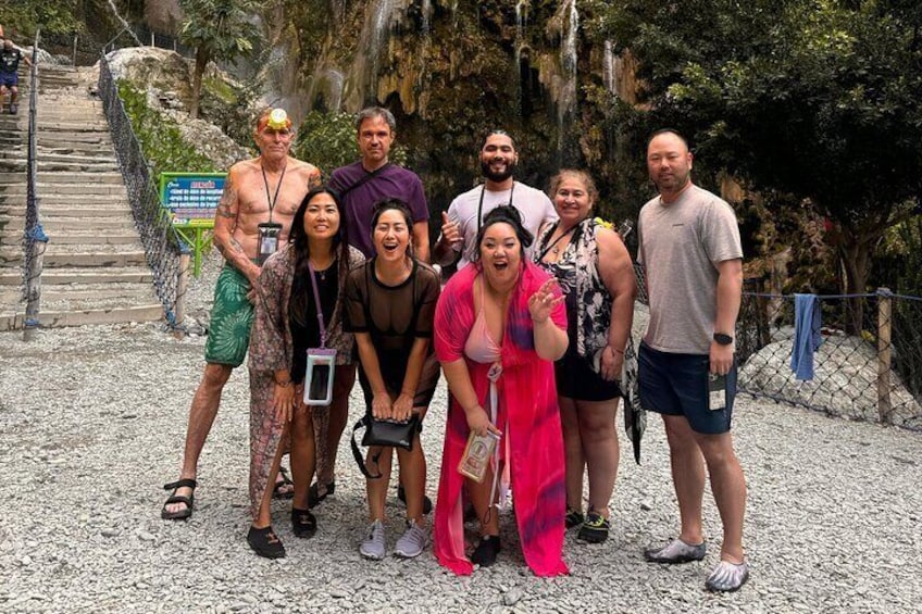 A group of people standing on a gravel path with a staircase and greenery in the background. 4