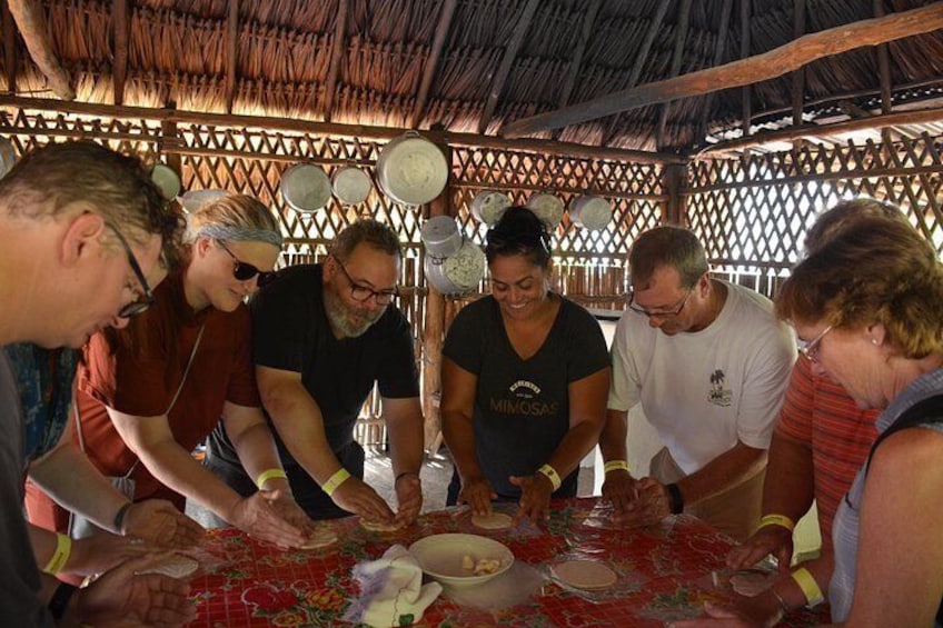 Un grupo de personas alrededor de una mesa con mantel rojo, participando en una actividad conjunta. 5