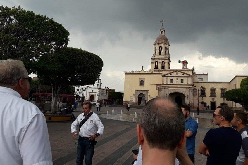 A group of people gathered in a plaza with a church in the background. 3