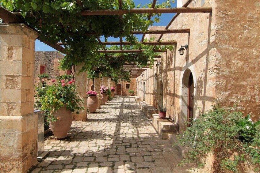 A cobblestone street with arches and potted plants. 4