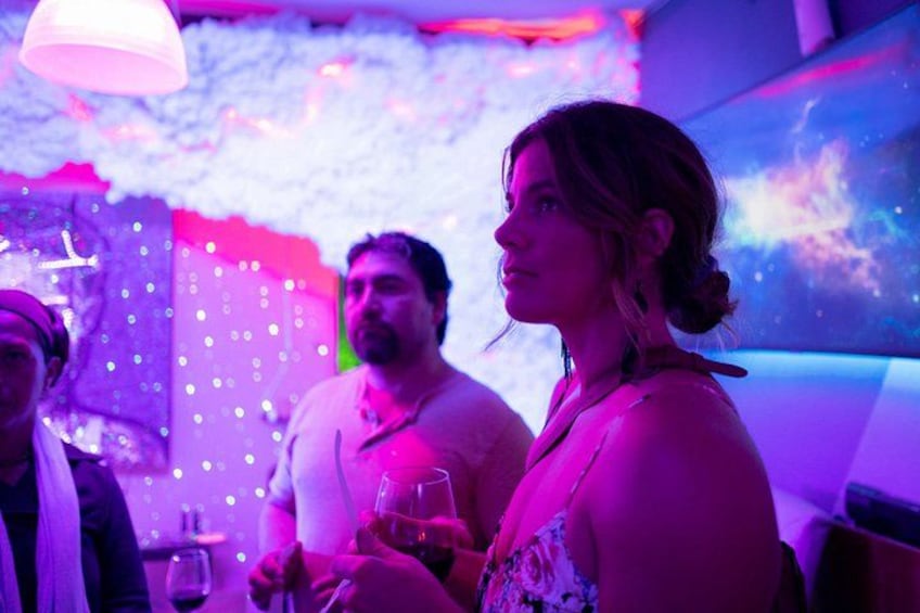 A person holding a glass, a decorative wall with lights, and a ceiling light fixture. 1