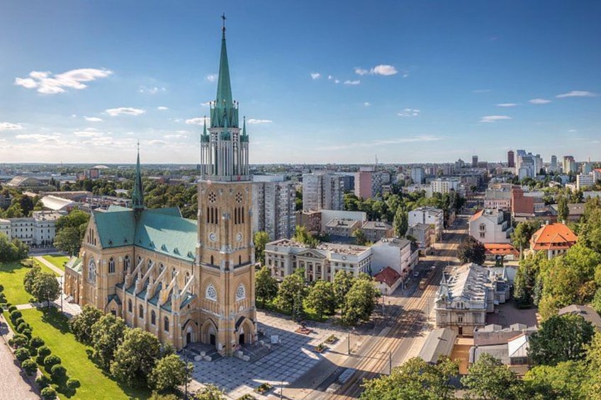Eine Kathedrale mit einem hohen Turm, umgeben von städtischen Gebäuden und blauem Himmel. 3