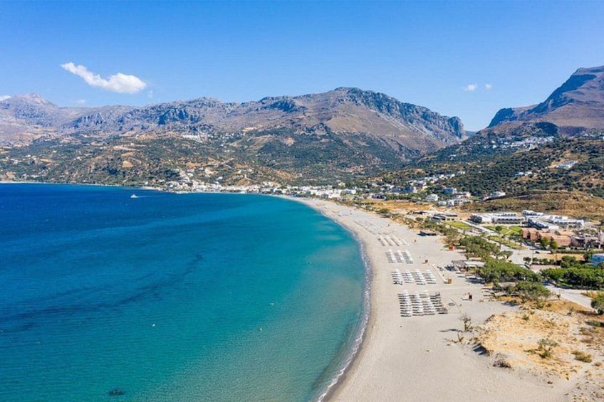 Un paisaje costero con una playa, aguas azules cristalinas y montañas al fondo. 2