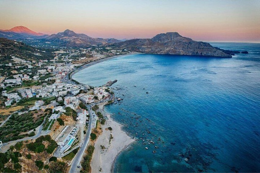 Un pueblo costero con una playa, una montaña al fondo y un cielo despejado. 1