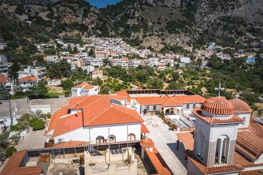 A mountainous town with terracotta-roofed buildings and a prominent church with a dome. 2