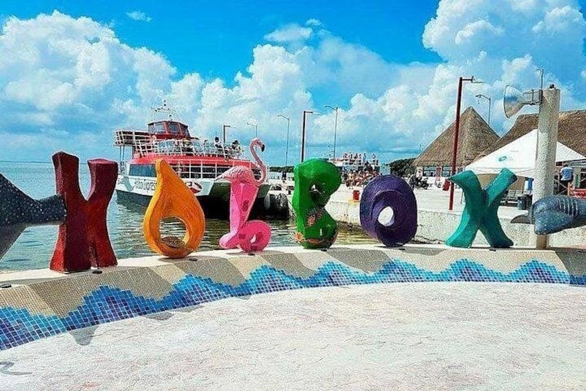 Colorful letter sculptures, a boat, and a beach with thatched-roof huts. 2