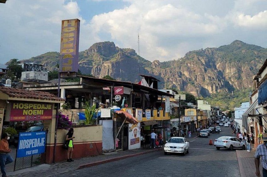 A street with shops, a hospital, and mountains in the background. 5
