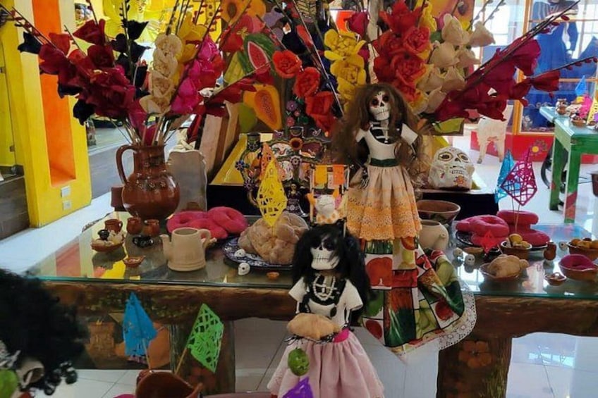 A display of colorful dolls and decorative items, including a skeleton doll and a vase with flowers. 3