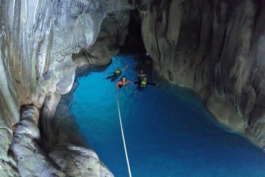 Une grotte avec un pont suspendu fait de cordes et deux personnes équipées de matériel de plongée sous-marine. 1
