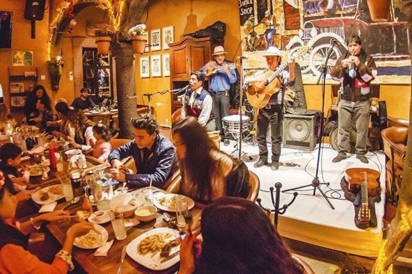 En restaurant med et liveband, gæster ved borde og en scene med musikinstrumenter. 2