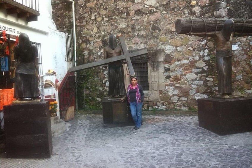 A cobblestone street with a woman standing in front of a stone wall with statues. 5