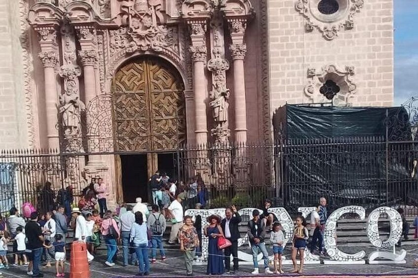 A crowd of people in front of a large, ornate building with a prominent entrance. 3
