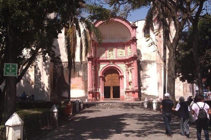 A historic building with a large archway, surrounded by trees and a paved walkway. 4