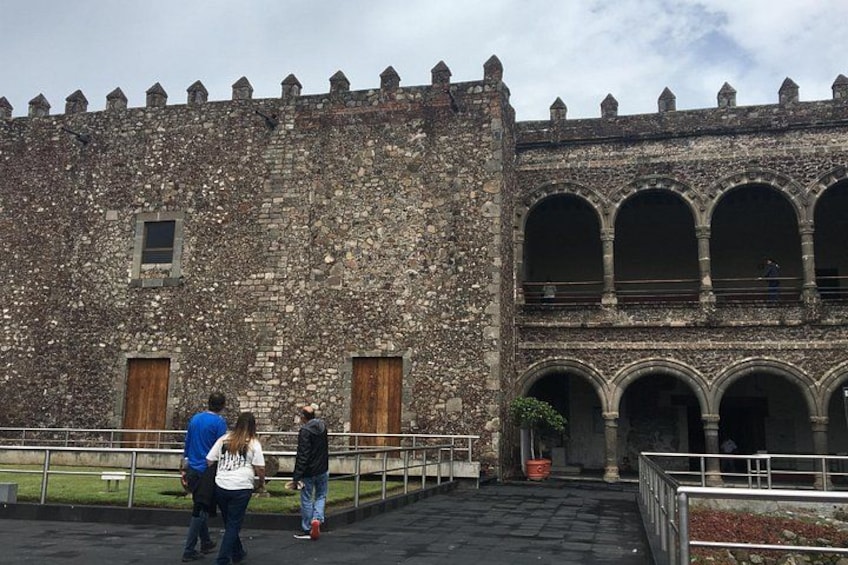 A historic stone building with arched windows and a courtyard. 1
