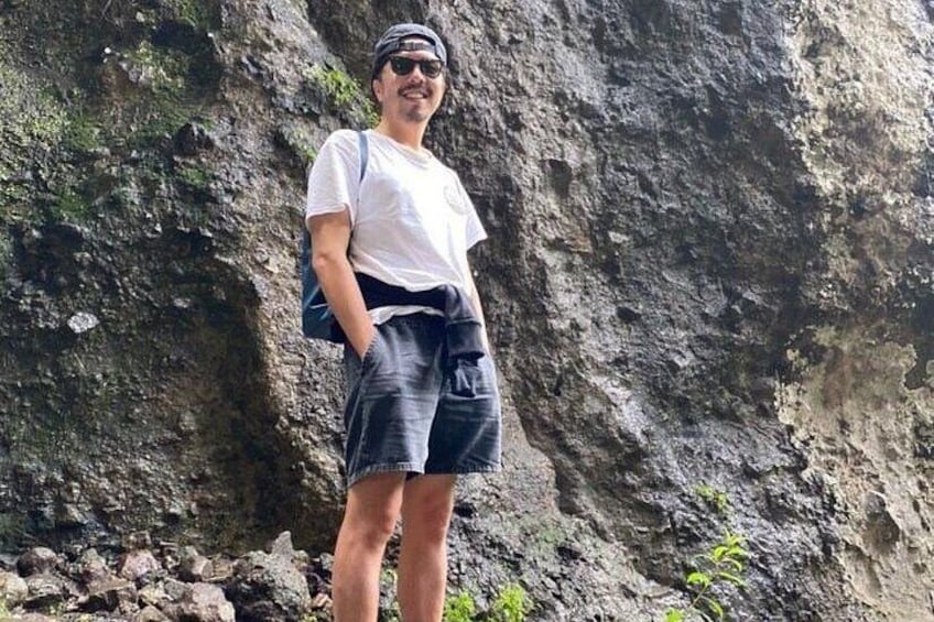 Una persona in piedi su un terreno roccioso, con una scogliera sullo sfondo. 1