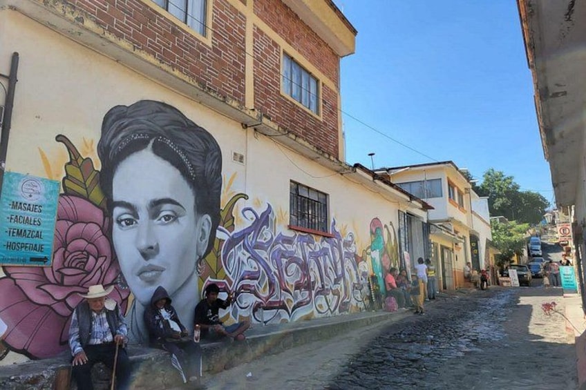 Una strada con un murale, un edificio e un cartello. 5