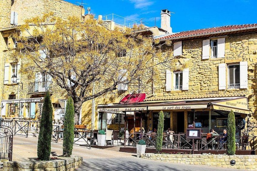 A stone building with a restaurant named 'La part des Anges' and outdoor seating. 1