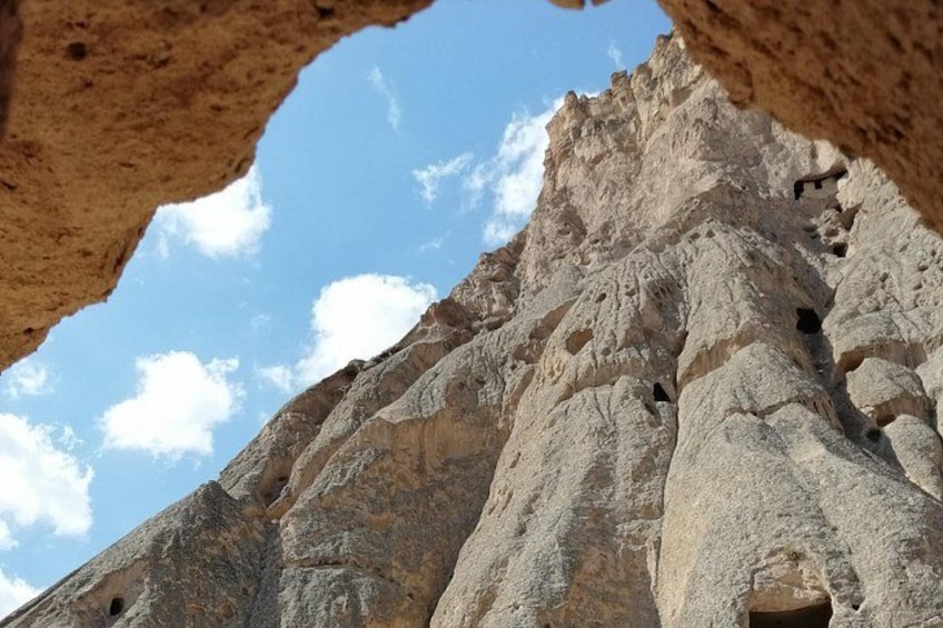 A rocky cliff with multiple caves and a clear sky. 2