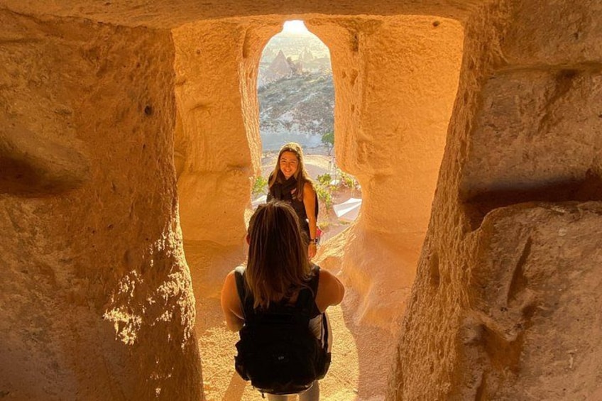 A person looking through a cave opening towards a mountainous landscape. 1