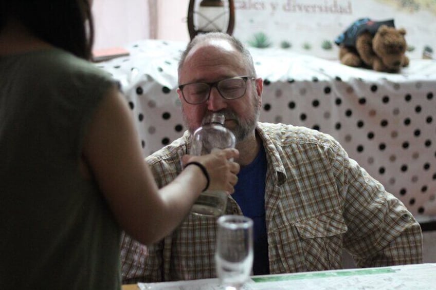 A person sitting at a table with a glass of water, a teddy bear in the background, and a polka dot tablecloth. 5
