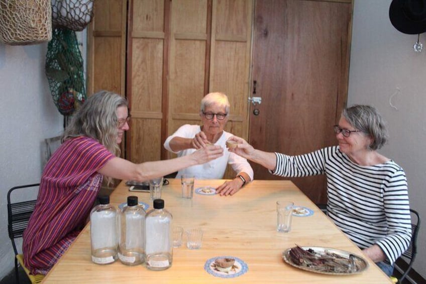 Three people sitting at a wooden table with salt shakers, a plate with food, and a glass. 3