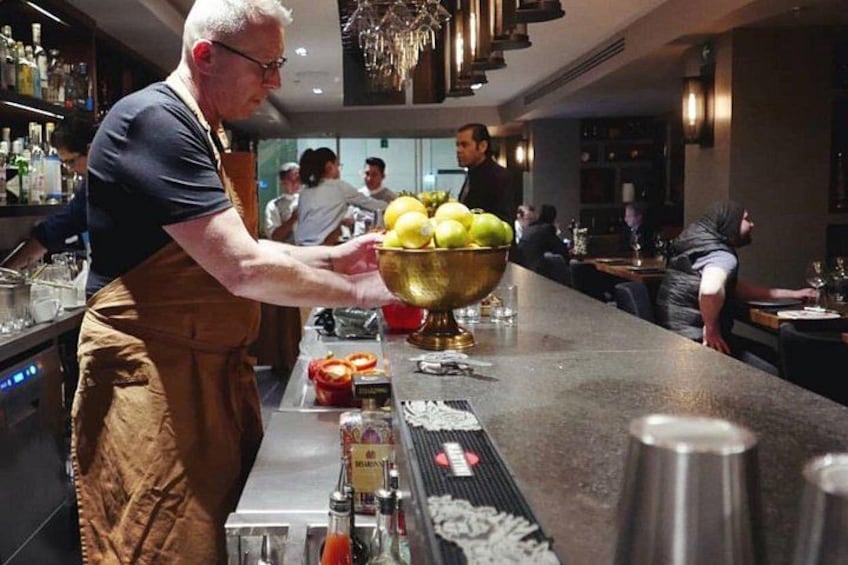 Un barman, derrière le comptoir d’un bar, devant un grand saladier rempli de citrons et une bouteille de sauce. 4