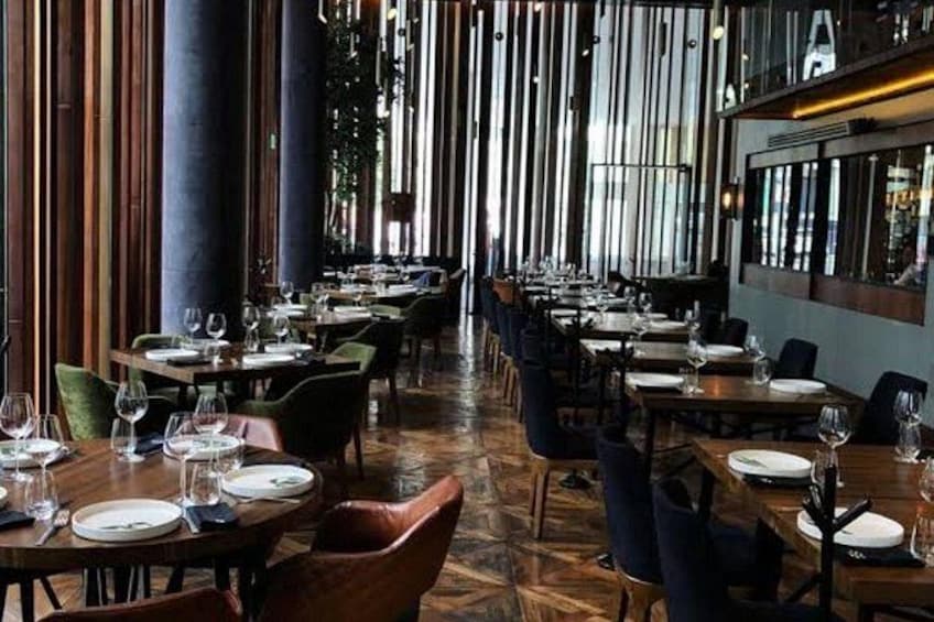 Un espace de restauration intérieur avec des murs lambrés, des tables dressées avec des assiettes et des verres, et des chaises. 5