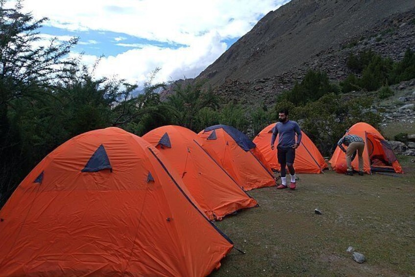 Orange tents set up in a mountainous area with a person standing in front of them. 1