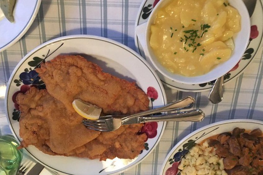 A meal with a breaded cutlet, a bowl of macaroni and cheese, and a plate of potatoes. 3