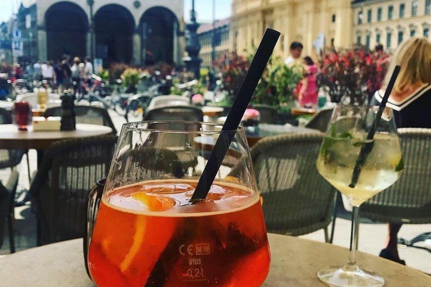 A glass of red drink with a black straw and an orange slice on a table. 5