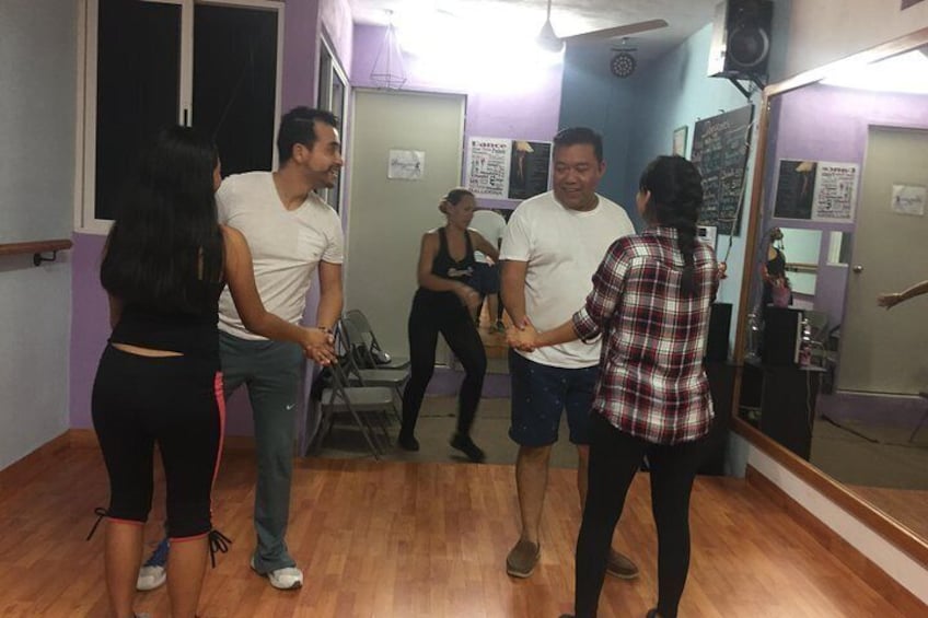 A group of people in a dance studio with wooden floors and mirrors. 5