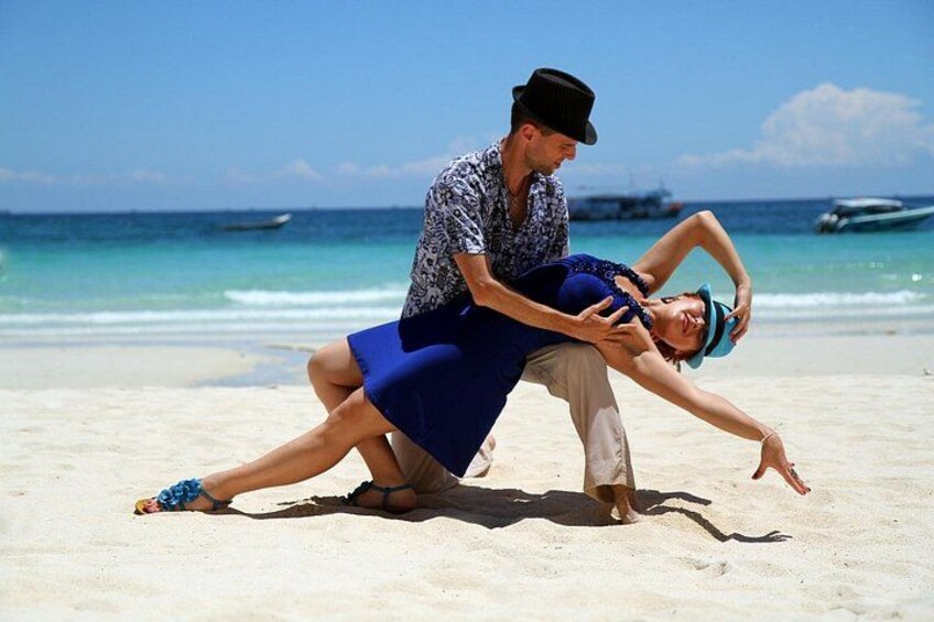 A couple on a beach with a boat in the background. 1