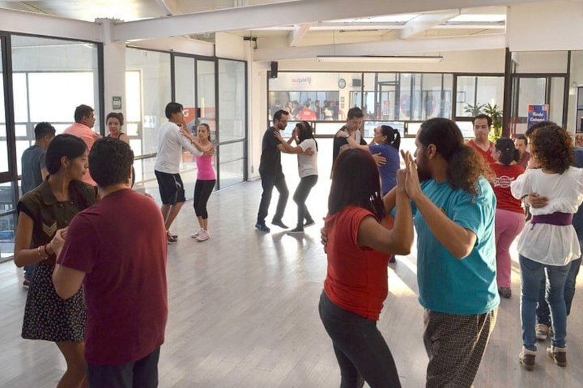Een groep mensen in een dansstudio met grote ramen en een houten vloer. 4