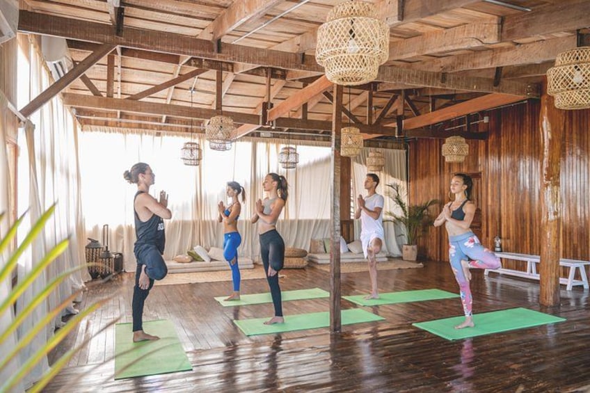 Una clase de yoga en una sala de madera con colchonetas verdes. 1