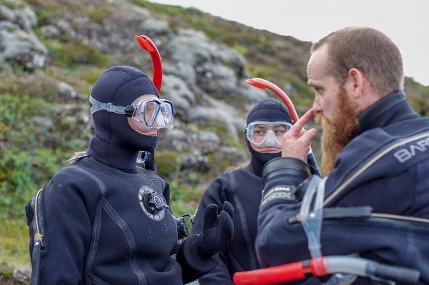 Deux personnes, équipées de matériel de plongée sous-marine et de palmes, se tiennent sur une côte rocheuse. 2