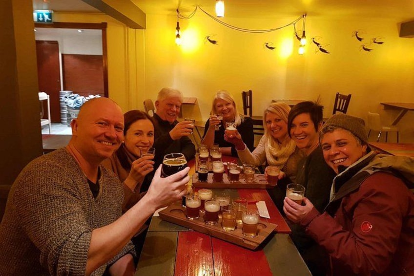 Un grupo de personas brindando con bebidas sentadas en una mesa en un ambiente cálidamente iluminado. 4