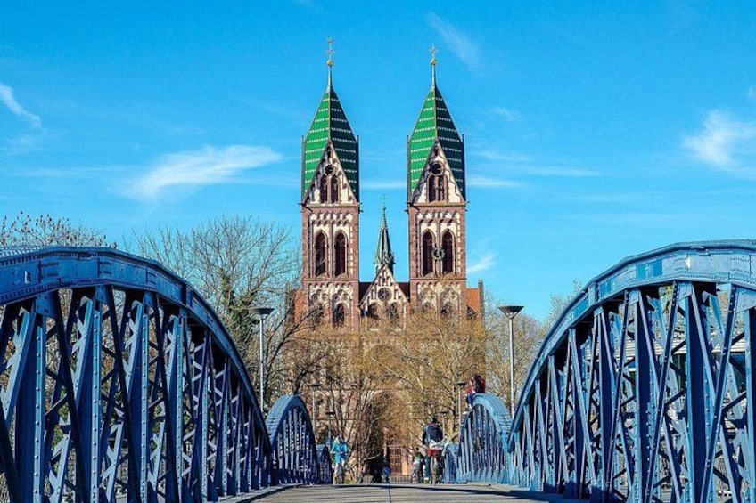 Eine Brücke mit zwei Türmen, eine Kirche mit grünen Spitzbögen und ein klarer, blauer Himmel. 1