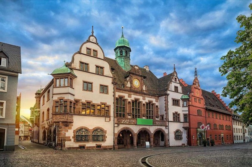 Ein historischer europäischer Stadtplatz mit Kopfsteinpflaster, traditioneller Architektur und einer Kirche mit einem Glockenturm. 2
