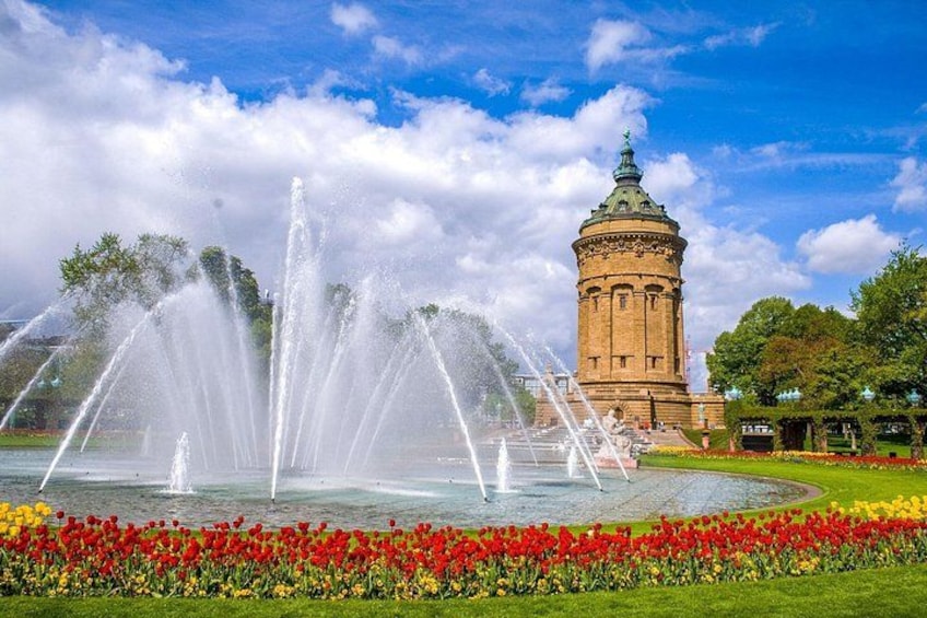 Una fuente de agua, una torre y un parterre de flores. 4