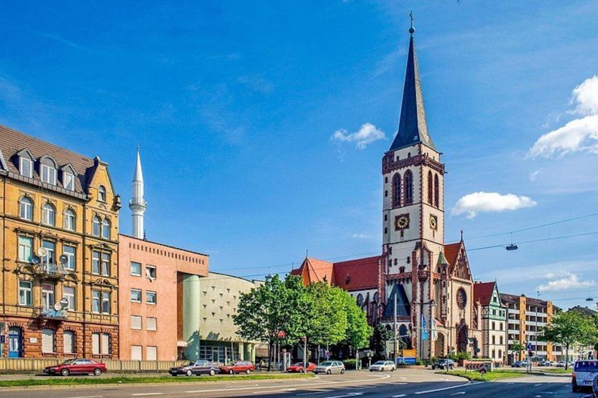Una iglesia con una aguja alta, una torre de reloj y un edificio de techo rojo. 3