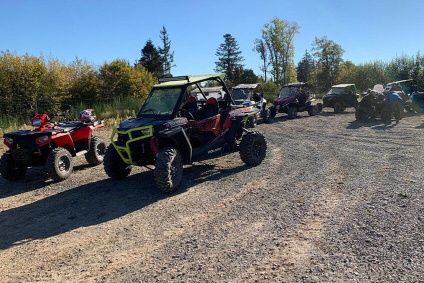 Off-road vehicles parked on a gravel surface with trees in the background. 4