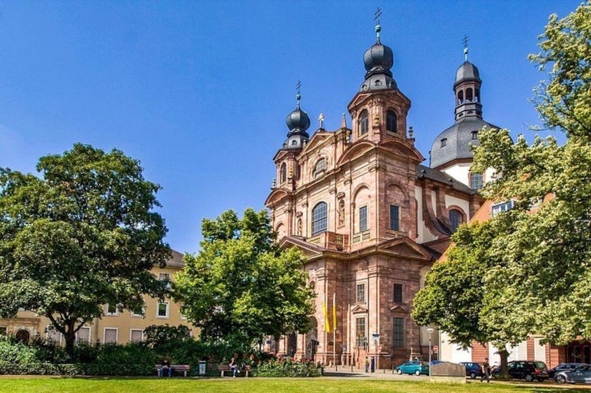 Una iglesia histórica con múltiples cúpulas y un campanario grande, rodeada de árboles y un césped bien cuidado. 5