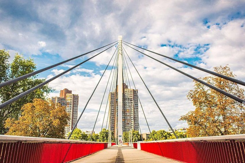 A cable-stayed bridge with red railings, a clear sky, and buildings in the background. 4