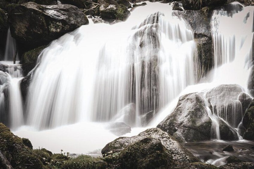 A waterfall cascading over rocks in a forested area. 3