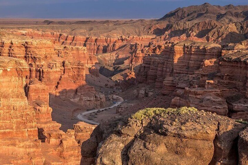 A canyon with layered rock formations and a winding road. 4