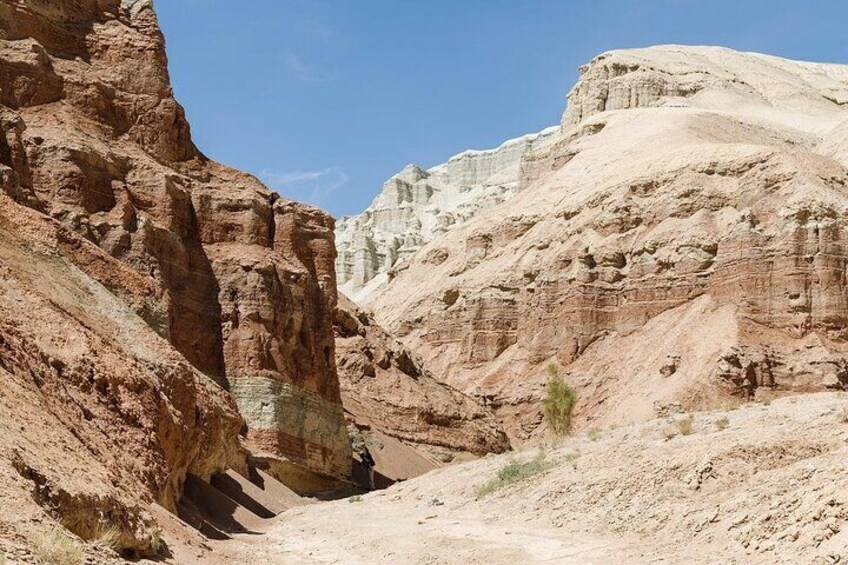 A canyon with layered rock formations and a narrow path. 3