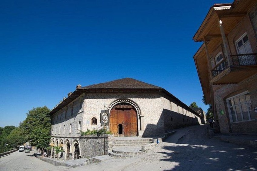 Un edificio histórico con una puerta de madera grande, ventanas arqueadas y fachada de piedra. 1
