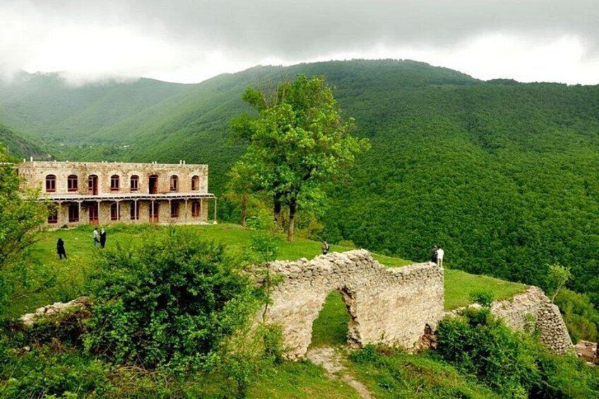 Un edificio histórico con ruinas, colinas verdes exuberantes y un cielo nublado. 5