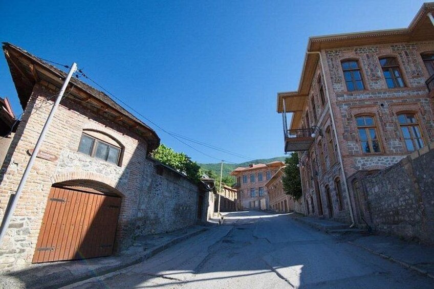 Una calle estrecha bordeada por edificios históricos con fachadas de piedra y puertas de madera. 2